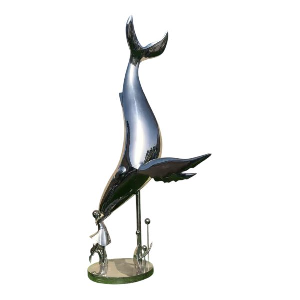 Shiny forged stainless steel whale sculpture jumping up in a curved pose.