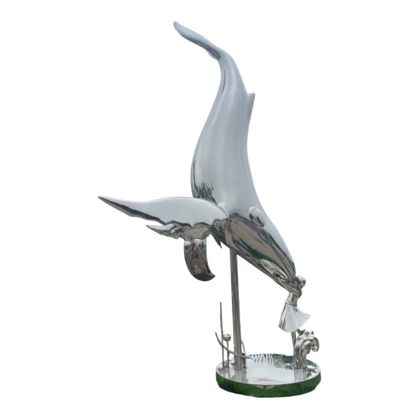 Shiny forged stainless steel whale sculpture jumping up in a curved pose.
