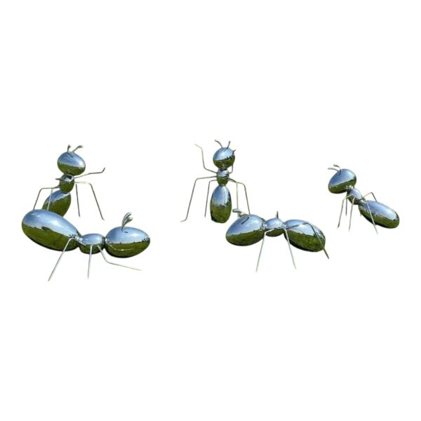 Polished stainless steel ant sculpture displayed outdoors on a grassy field